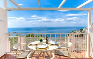 Ein Balkon mit Tisch für zwei Personen, mit Blick auf die Küste.