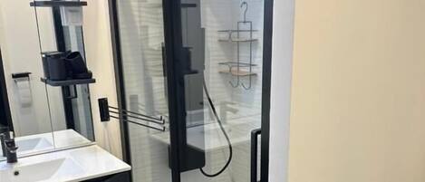 Une salle de bain moderne avec une douche à parois de verre, un lavabo blanc et un meuble-lavabo aux tons foncés.