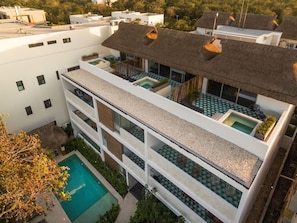 Un edificio de varios pisos con piscina, balcones y techo de paja.