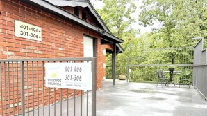 A brick building with a sign indicating studio rental information and a gated entrance. - Eureka Vibes | Walk to Downtown + Trolley unit 405 (Eureka Springs)