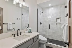 A modern bathroom with a large mirror, a sink, a toilet, and a glass-enclosed shower area. - 3BR Chef Kitch GameRM BBQ Steps to Hike Bike Golf Spa (Cle Elum)
