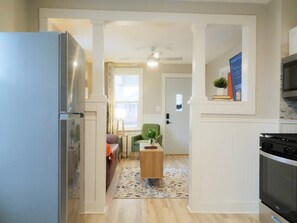 A modern kitchen with a refrigerator, stove, and microwave. There is a dining area with a table and chairs. - Cozy 2BR | WiFi + Kitchen | Extended Stay (East Peoria)