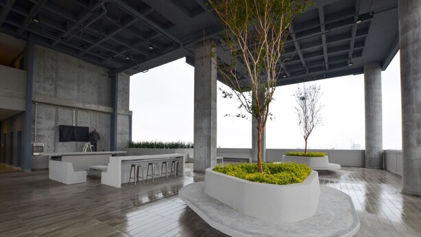 A spacious indoor area with a central seating area, a bar, and a large window providing a view.