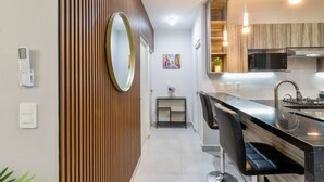 A modern kitchen with a black countertop, stainless steel appliances, and a wooden accent wall.