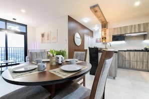A modern dining area with a round table, chairs, and a view of the city through large windows. - ¡A pasos de Fundidora! Wifi + Cajón | 2BR2br 6ppl (Monterrey)