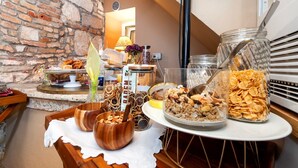 Un bufé de desayuno con diversas opciones de comida y una pared de ladrillo rústica al fondo.