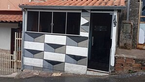 A small building with a tiled roof, a black door, and a patterned wall.