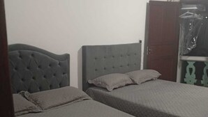 A room with two beds, a wardrobe, and a door.