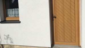 A white building with a window and a wooden door. - 5 minutes to the center, 5 minutes to the forest, a cozy little apartment (Selb)