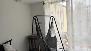 A room with a bed, a hammock chair, a small table, and a window with curtains. - 5 minutes to the center, 5 minutes to the forest, a cozy little apartment (Selb)