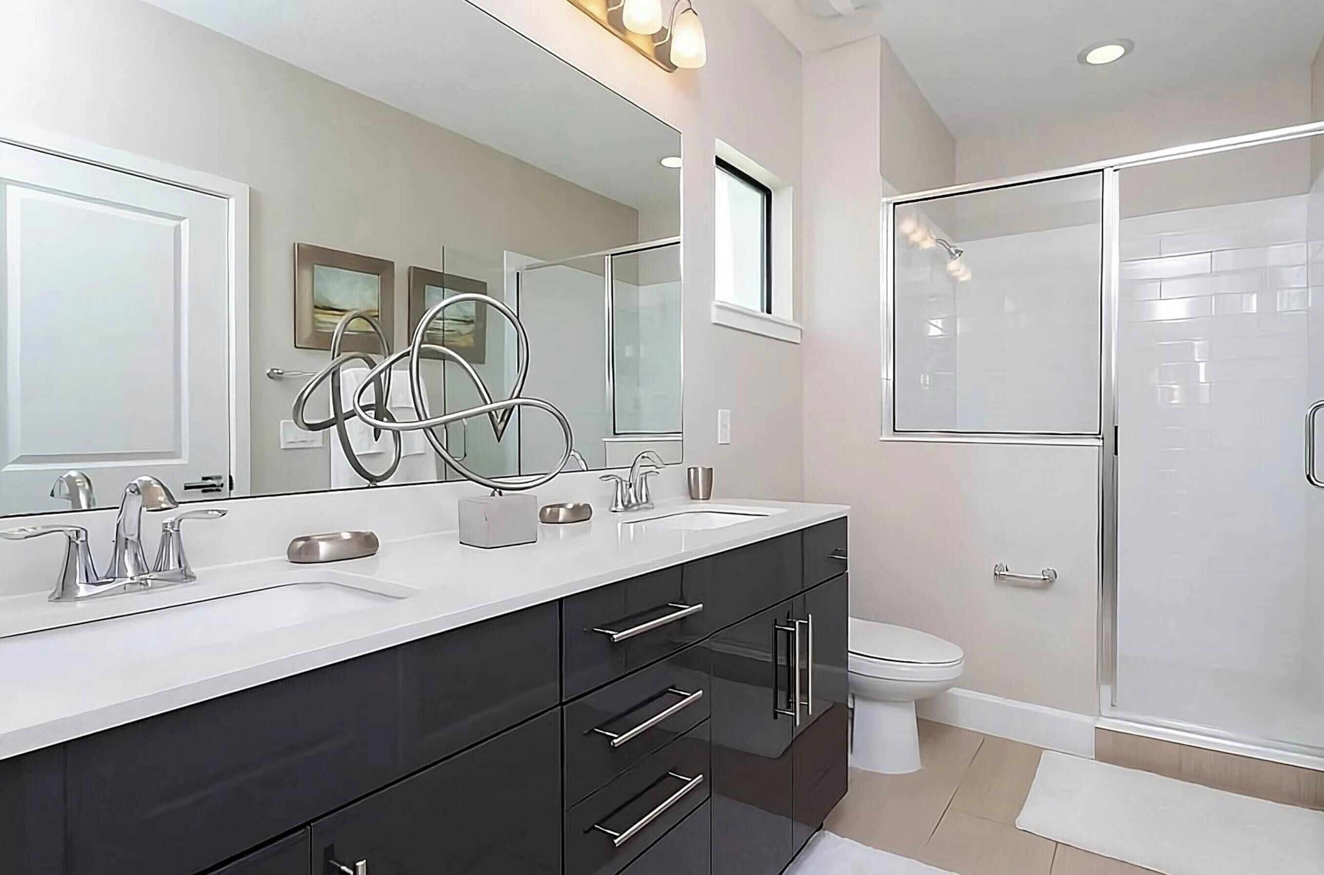 Un bagno moderno con un doppio lavabo, box doccia in vetro e water.