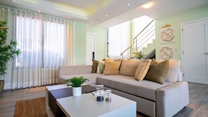Een moderne woonkamer met een bank, salontafel en trap.
