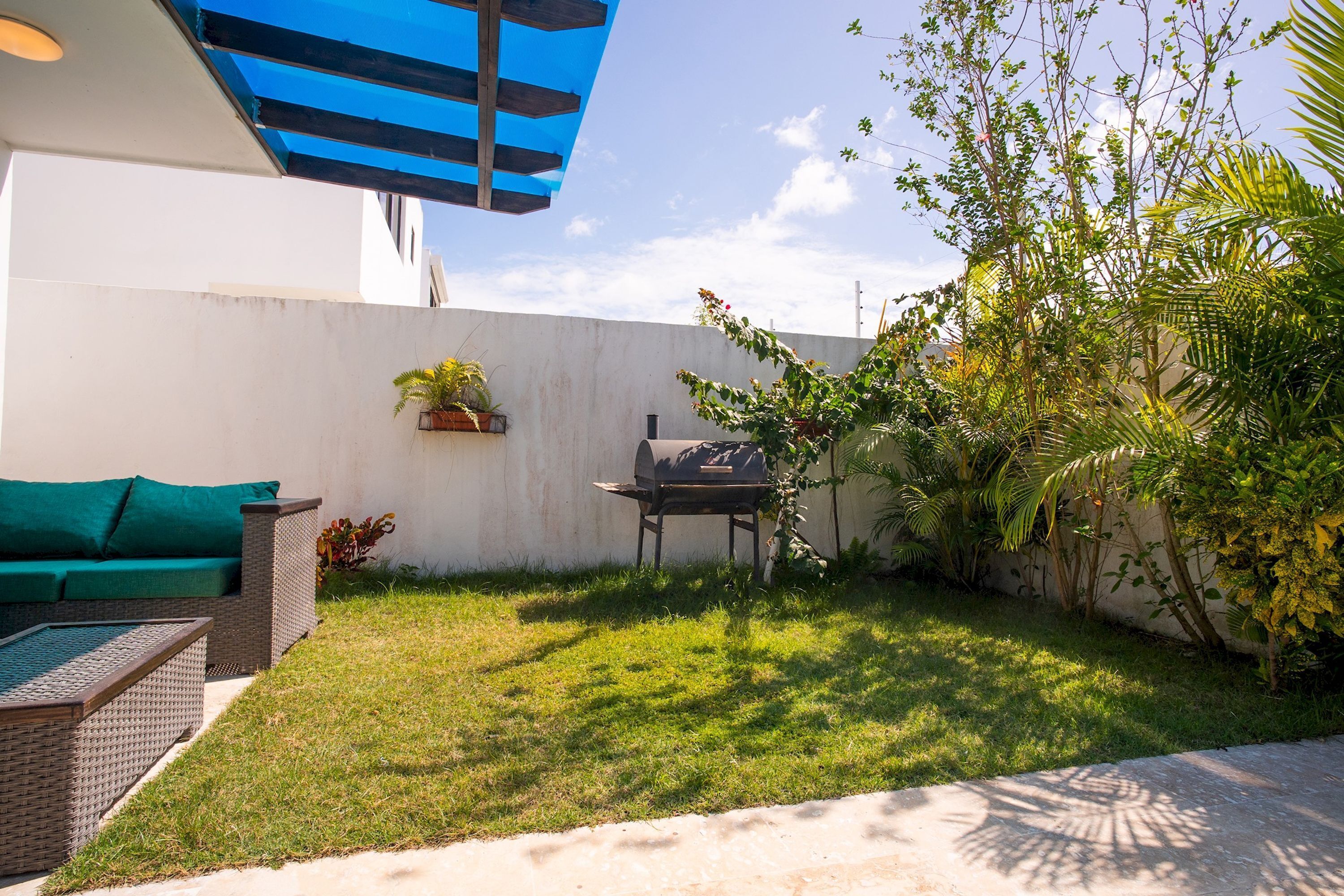 A patio with a grill, a sofa, and potted plants.