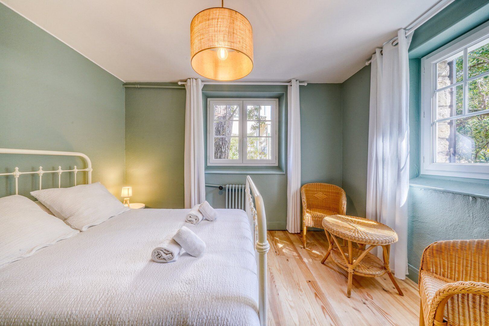 Ein Schlafzimmer mit einem Bett, einem Stuhl, einem Fenster und einer Lampe.