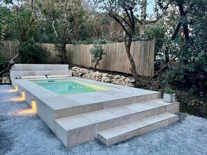 A rectangular pool with steps leading up to it, surrounded by a wooden fence and trees. - La Villa Pylataise – Pyla sur mer- Swimming pool (Pyla sur Mer)