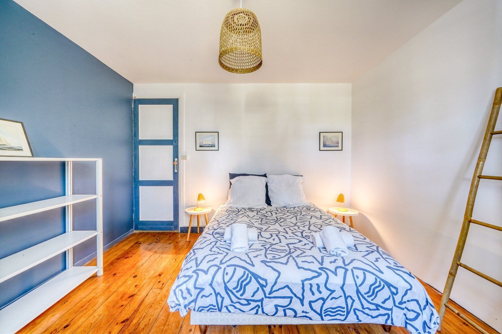 Une chambre à coucher comprenant un lit, deux tables de chevet, une lampe sur pied, une étagère et une porte.