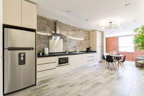 Een moderne keuken met een roestvrijstalen koelkast, een inbouwoven en een groot kookeiland met zitplaatsen.