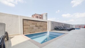 A rooftop pool area with a tiled floor, a wooden wall, and lounge chairs. - ¡A pasos de la Macroplaza! Alberca y Gimnasio (Monterrey)