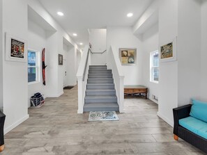 A hallway with a staircase, wooden flooring, and framed artwork on the walls. - Stunning 4 br/ 5 bath Navarre Beach Home with waterfront access (Navarre Beach)