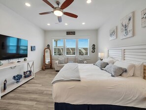 A bedroom with a bed, a TV, a ceiling fan, and a window with a view. - Stunning 4 br/ 5 bath Navarre Beach Home with waterfront access (Navarre Beach)