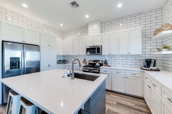 Una cocina moderna con armarios blancos, electrodomésticos de acero inoxidable y una isla grande.