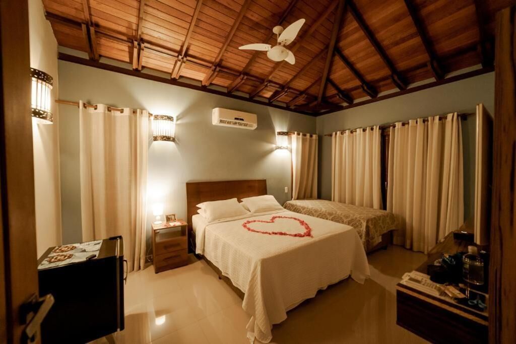 A bedroom with a bed, a ceiling fan, a nightstand, a dresser, and a desk with a lamp.
