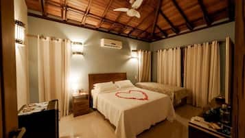 A bedroom with a bed, a ceiling fan, a nightstand, a dresser, and a desk with a lamp.