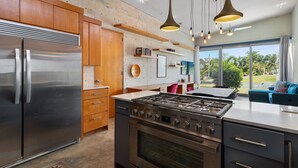 A modern kitchen with stainless steel appliances, wooden cabinets, and pendant lighting. - Two bedroom  in Puerto Rico, Aguada (Aguada)
