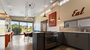 A modern kitchen with a large island, stainless steel appliances, pendant lighting, and a view of the outdoors. - Two bedroom  in Puerto Rico, Aguada (Aguada)