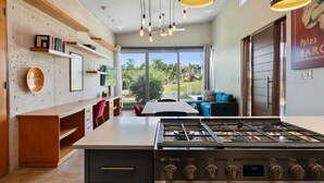 A modern kitchen with a gas stove, wooden shelves, and a view of the outdoors. - Two bedroom  in Puerto Rico, Aguada (Aguada)