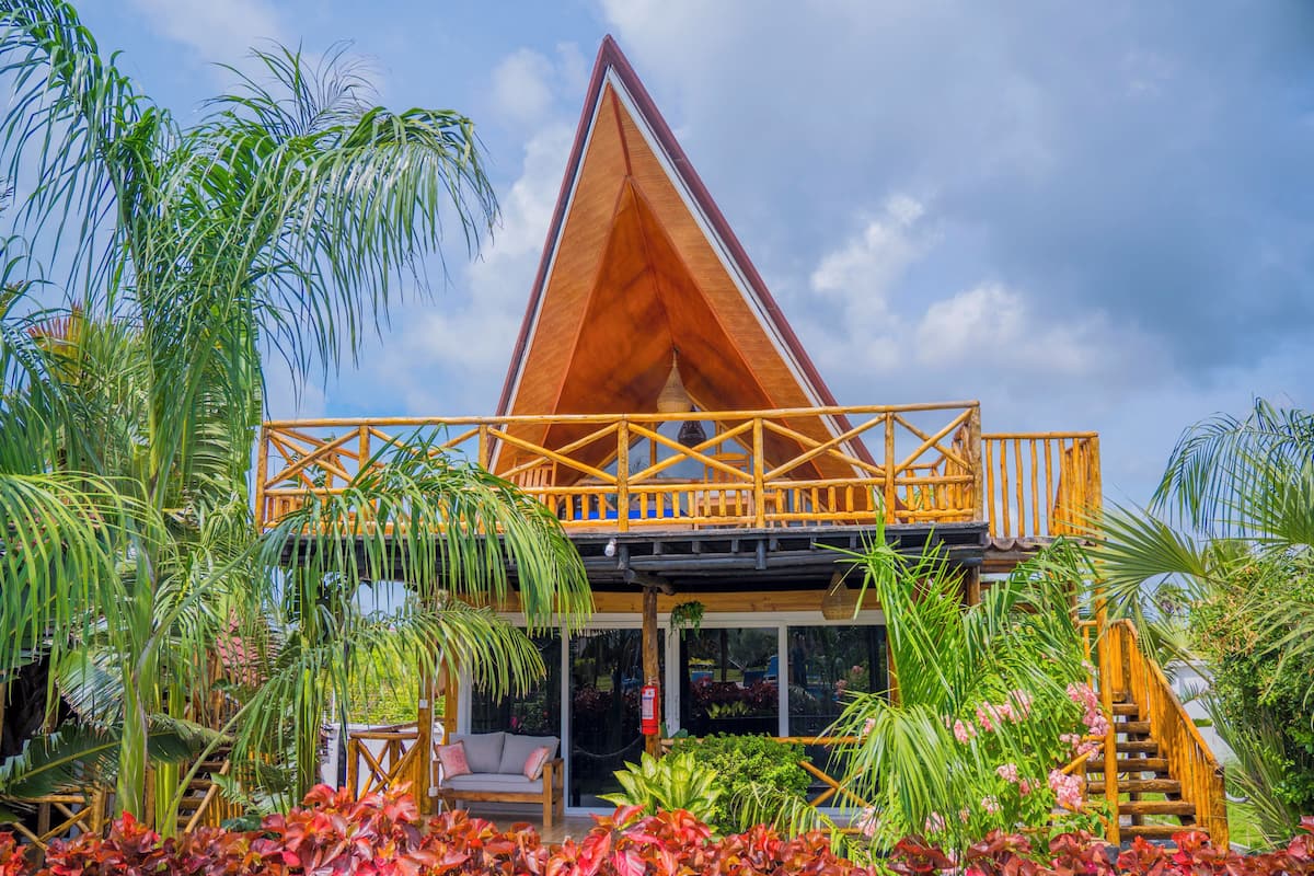 Una estructura de madera con balcón, rodeada de plantas tropicales.