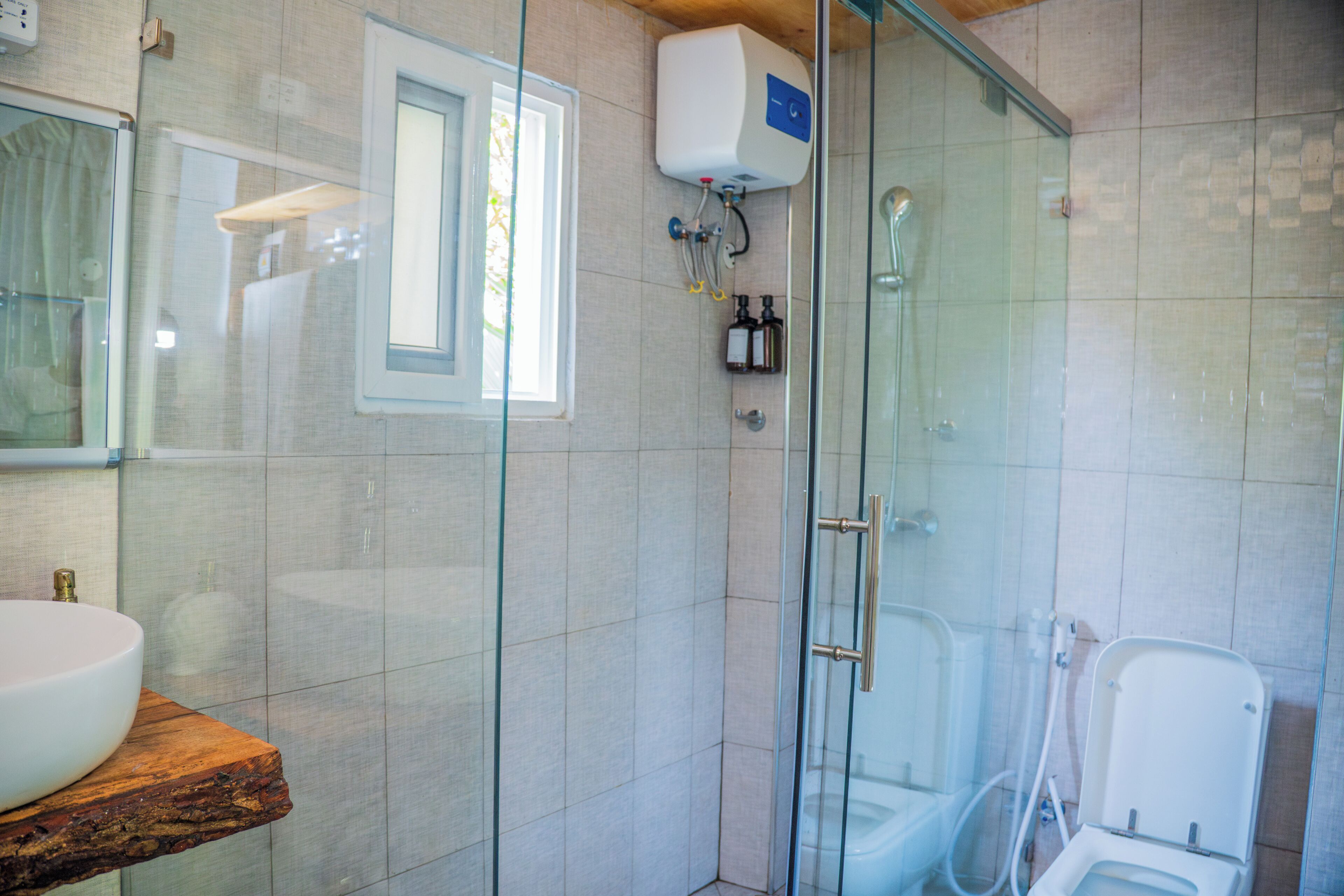 A modern bathroom with a glass-enclosed shower, a toilet, and a sink on a wooden countertop.