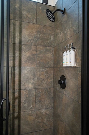 A shower with a handheld showerhead, a glass enclosure, and toiletries. - Busted Pallet (Anderson)