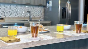 Et moderne køkken med marmor bordplade, kaffemaskine og skål med frugt.