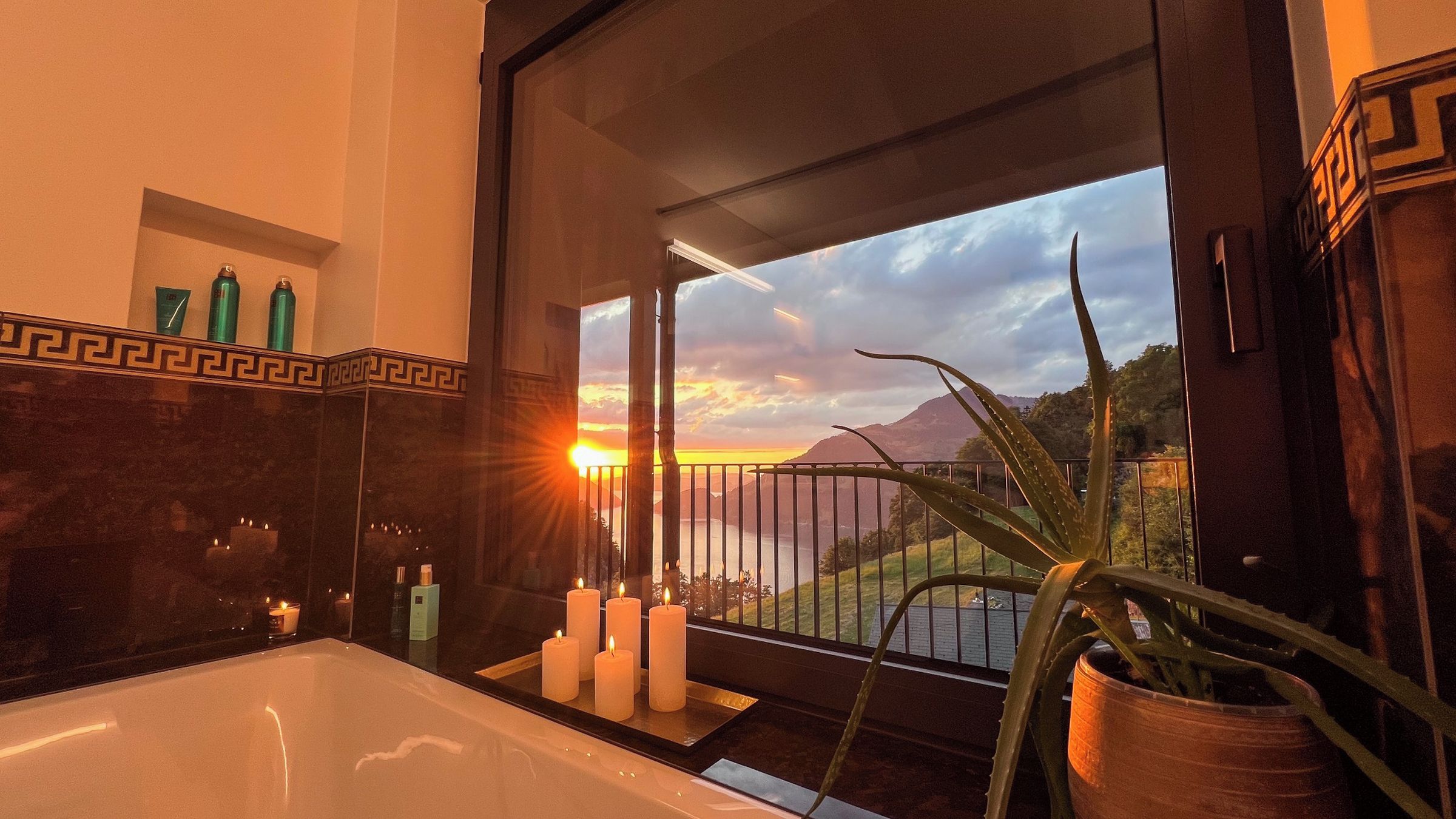 A bathroom with a bathtub, candles, and toiletries on the counter.