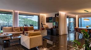 A modern living room with a sofa, coffee table, and a dining area with chairs and a table.