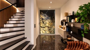 A modern interior with a staircase, a stone wall, and a bookshelf.