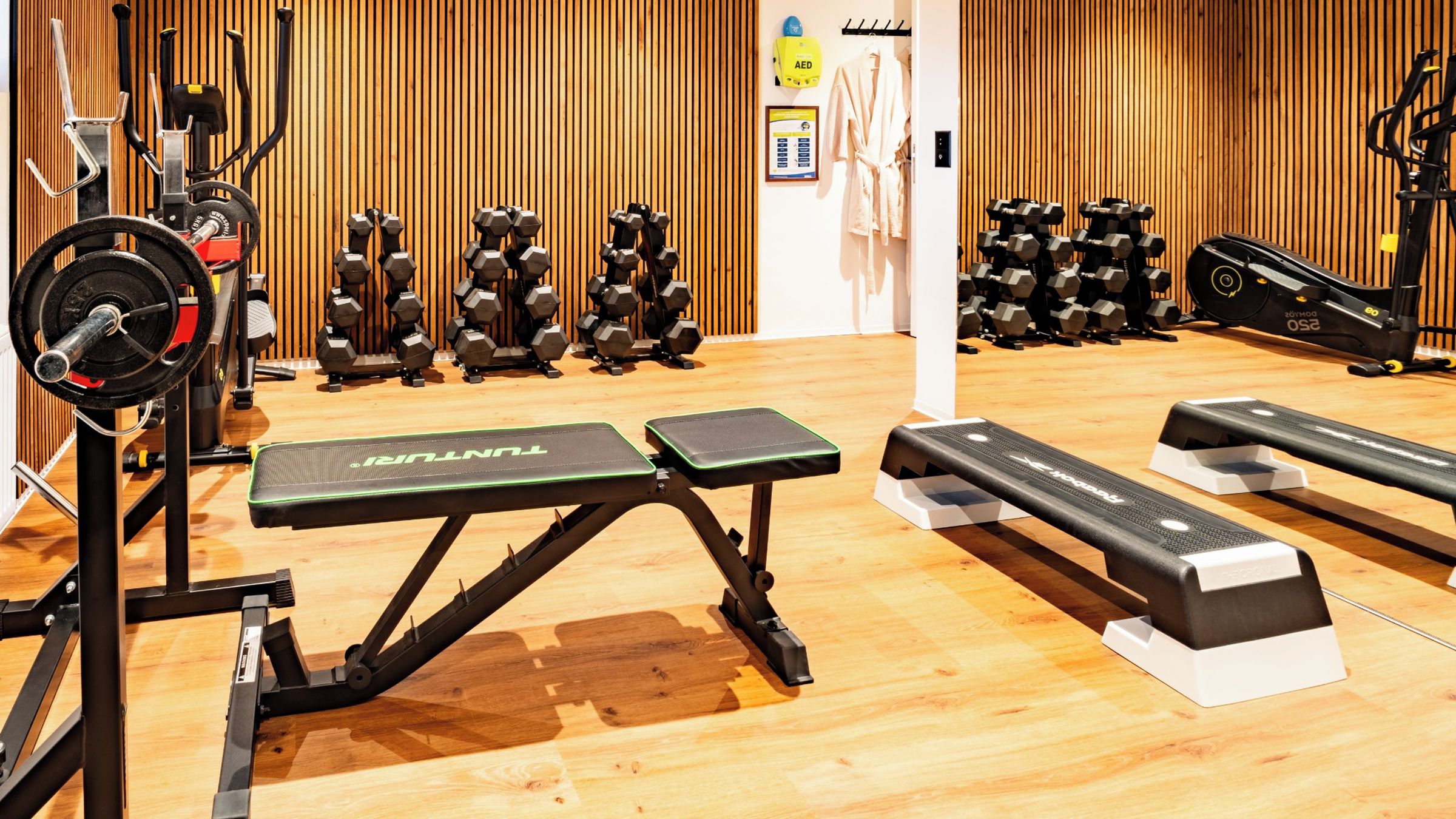 A gym with various exercise equipment, including dumbbells, a bench press, and a stationary bike.