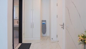 Ein Flur mit einem weißen Kleiderschrank, einem gemusterten Wäscheständer und einer Tür mit Griff.