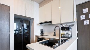 Una cocina moderna con lavavajillas integrado, un lavamanos de acero inoxidable y un refrigerador negro.