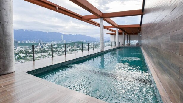 Una piscina interior con vista a un paisaje urbano y montañas.