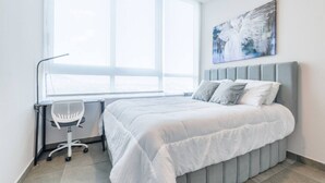 Un dormitorio con cama, escritorio y ventana.