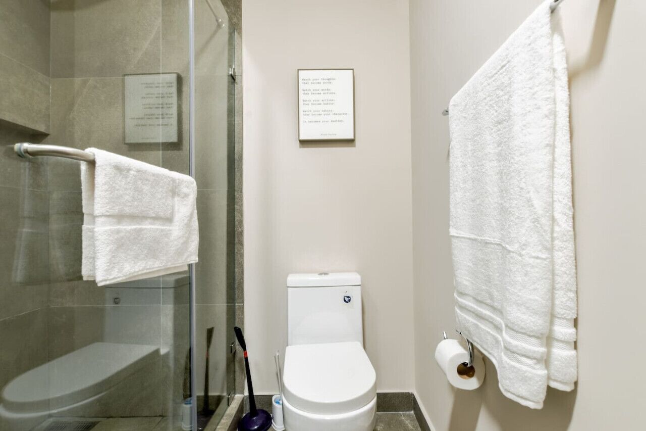 A bathroom with a glass shower enclosure, a toilet, and a towel rack.