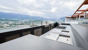 Eine moderne Küche mit Stadtblick, inklusive integriertem Grill und großem Fenster zur Stadtansicht.