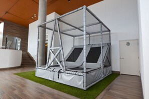 Una habitación con un amplio espacio de juego cerrado, techo y paredes de malla, una escalera y una puerta.