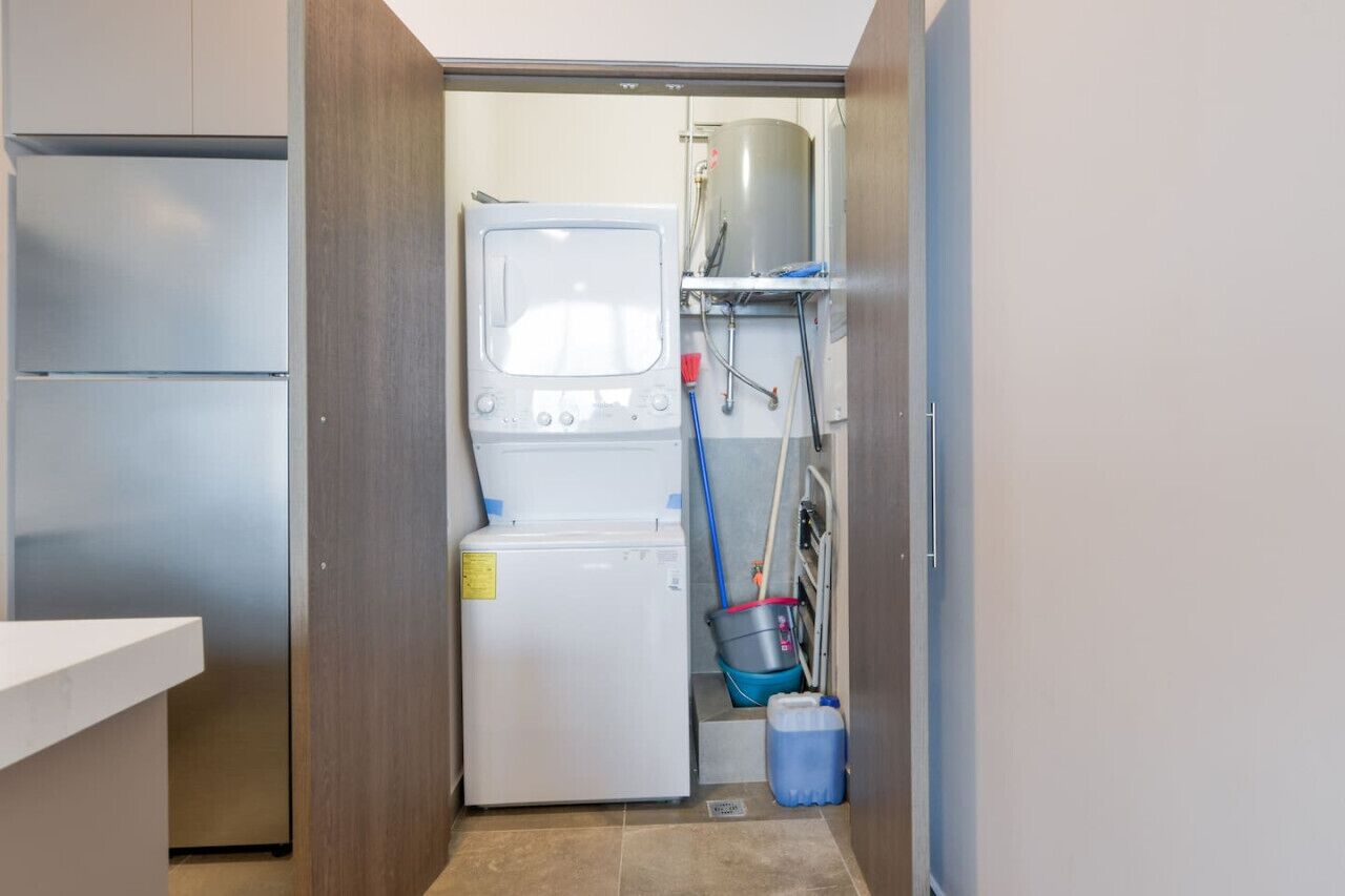 A compact laundry room with a washing machine, a dryer, a water heater, and a mop bucket.