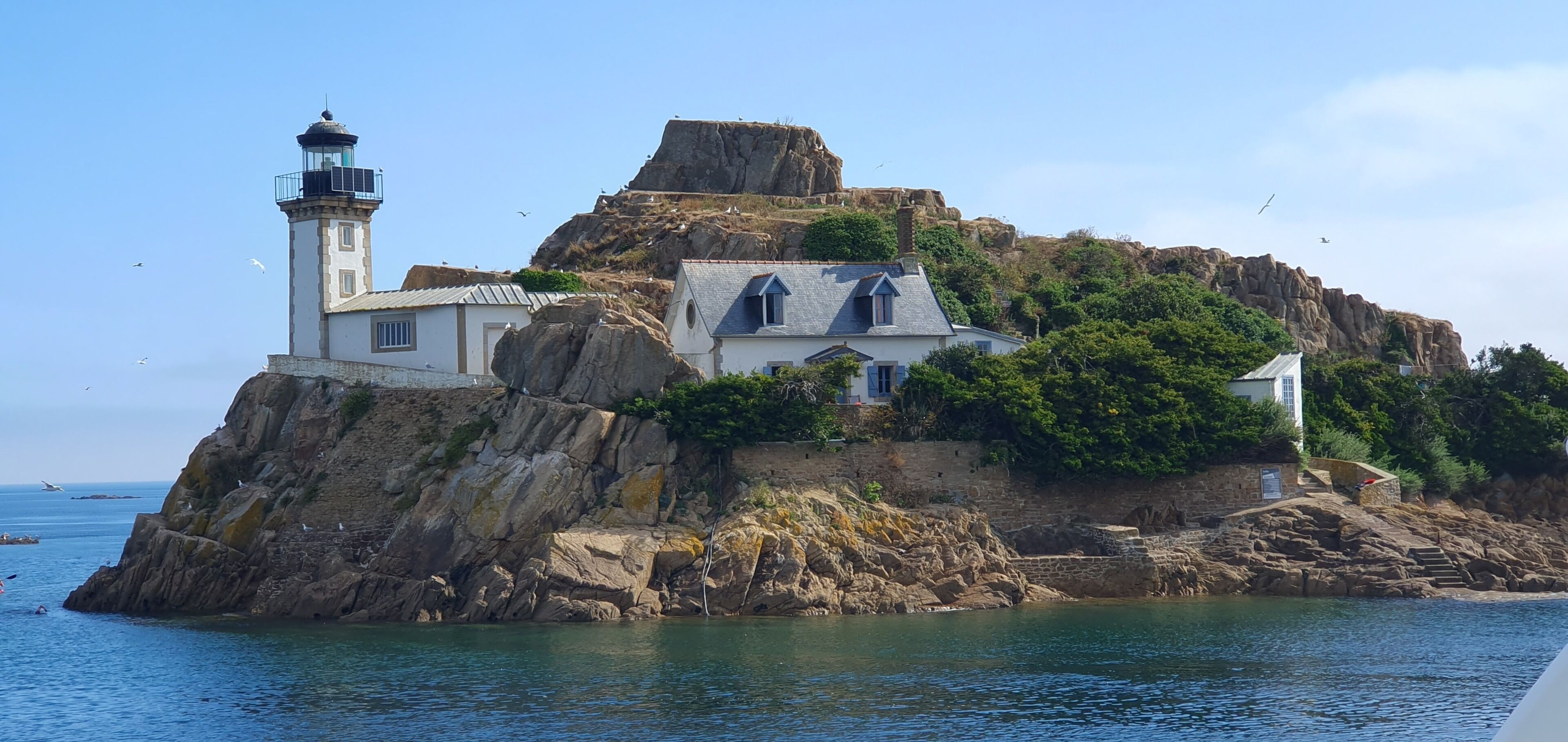A coastal building with a lighthouse, situated on a rocky outcrop with a view of the sea.
