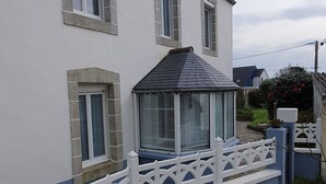 Una casa a due piani con esterno bianco, una sezione inferiore blu e un recinto in legno bianco.