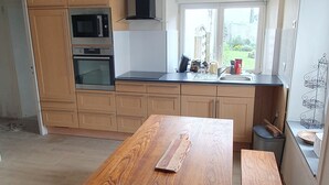 Una cucina moderna con mobili in legno, un tavolo di legno grande e una finestra che offre vista all'esterno.