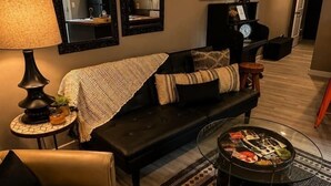 Un salon avec un canapé, une table basse, une lampe et un miroir fixé au mur.